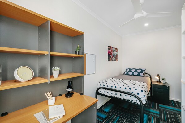 Une chambre moderne équipée d’un lit, d’un bureau, d’étagères et d’un ventilateur de plafond.