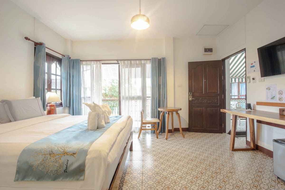 Ein Hotelzimmer mit Bett, Schreibtisch, Stuhl, Fernseher und einem Fenster mit Vorhängen.