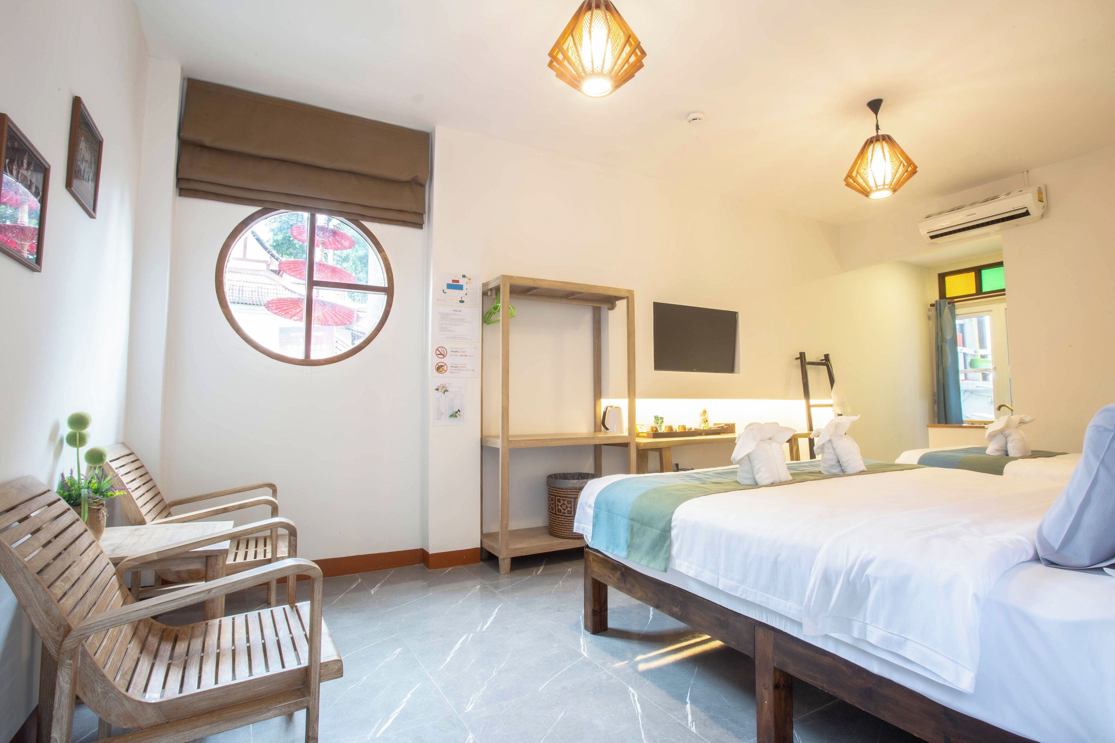 A hotel room with a bed, wooden chairs, a desk, a window, and a TV.