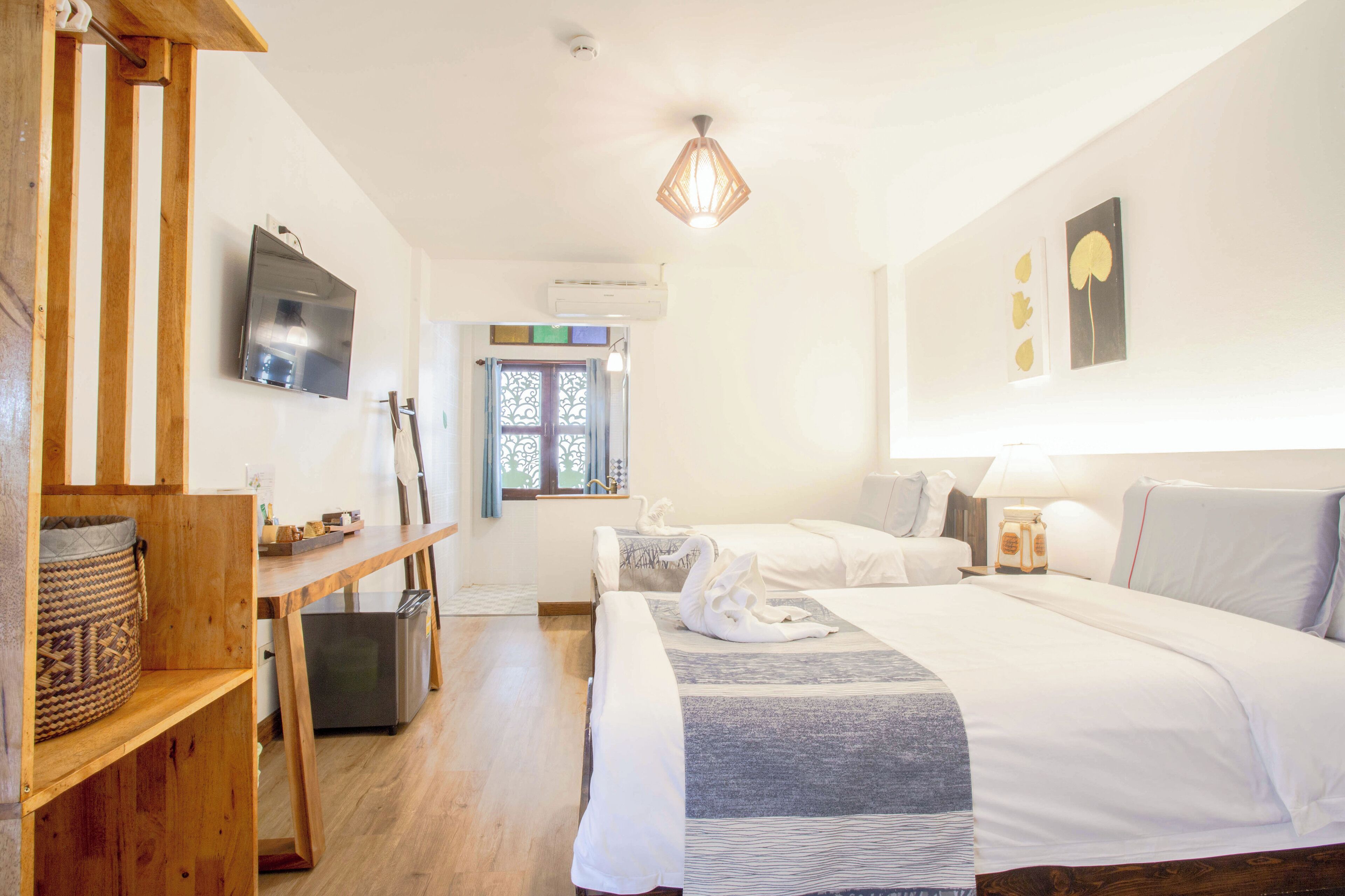 Un dormitorio con cama, mesita de noche y televisor en la pared.
