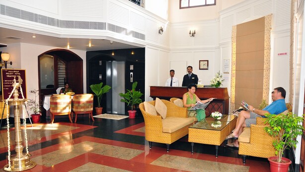 A hotel lobby with a reception desk, seating area, and a decorative lamp. - V K G Group Holiday Hotel (Kochi)