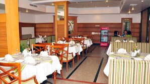 A restaurant with wooden chairs and tables, a Coca-Cola refrigerator, and a 'No Smoking Area' sign. - V K G Group Holiday Hotel (Kochi)