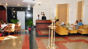A hotel lobby with a reception desk, seating area, and a decorative lamp. - V K G Group Holiday Hotel (Kochi)