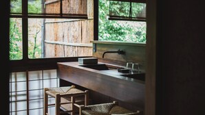 Una cocina con encimera de madera, un fregadero y una ventana con vistas a una valla de madera y follaje.