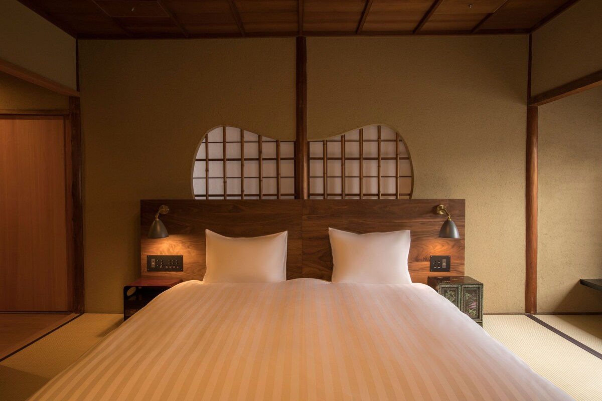 A traditional Japanese-style bedroom with tatami flooring, a low wooden headboard, and two bedside lamps.