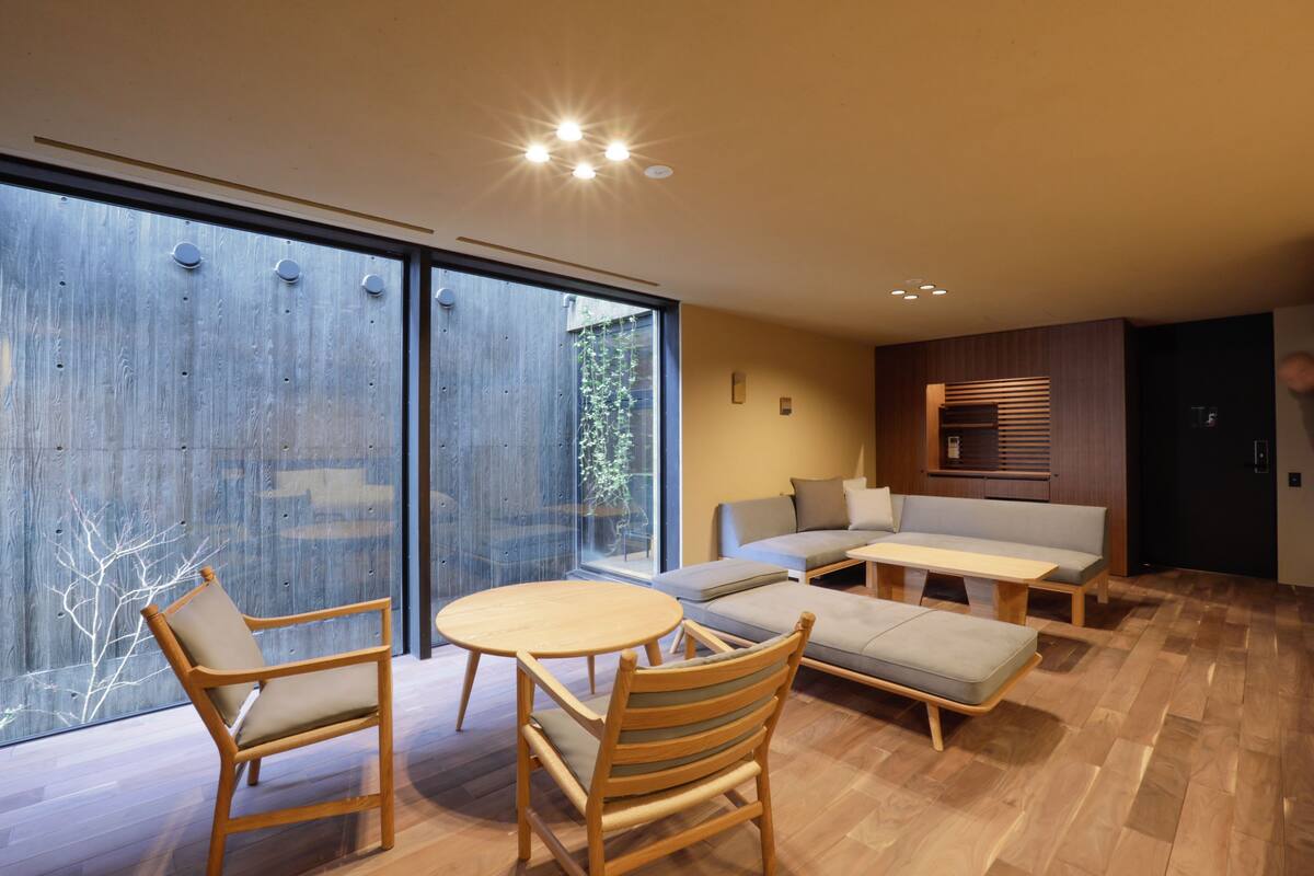 Een moderne woonkamer met houten vloer, een bank, een salontafel en twee fauteuils.