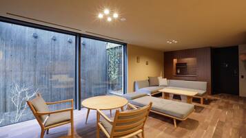 Un salon moderne avec un plancher en bois, un canapé, une table basse et deux fauteuils.