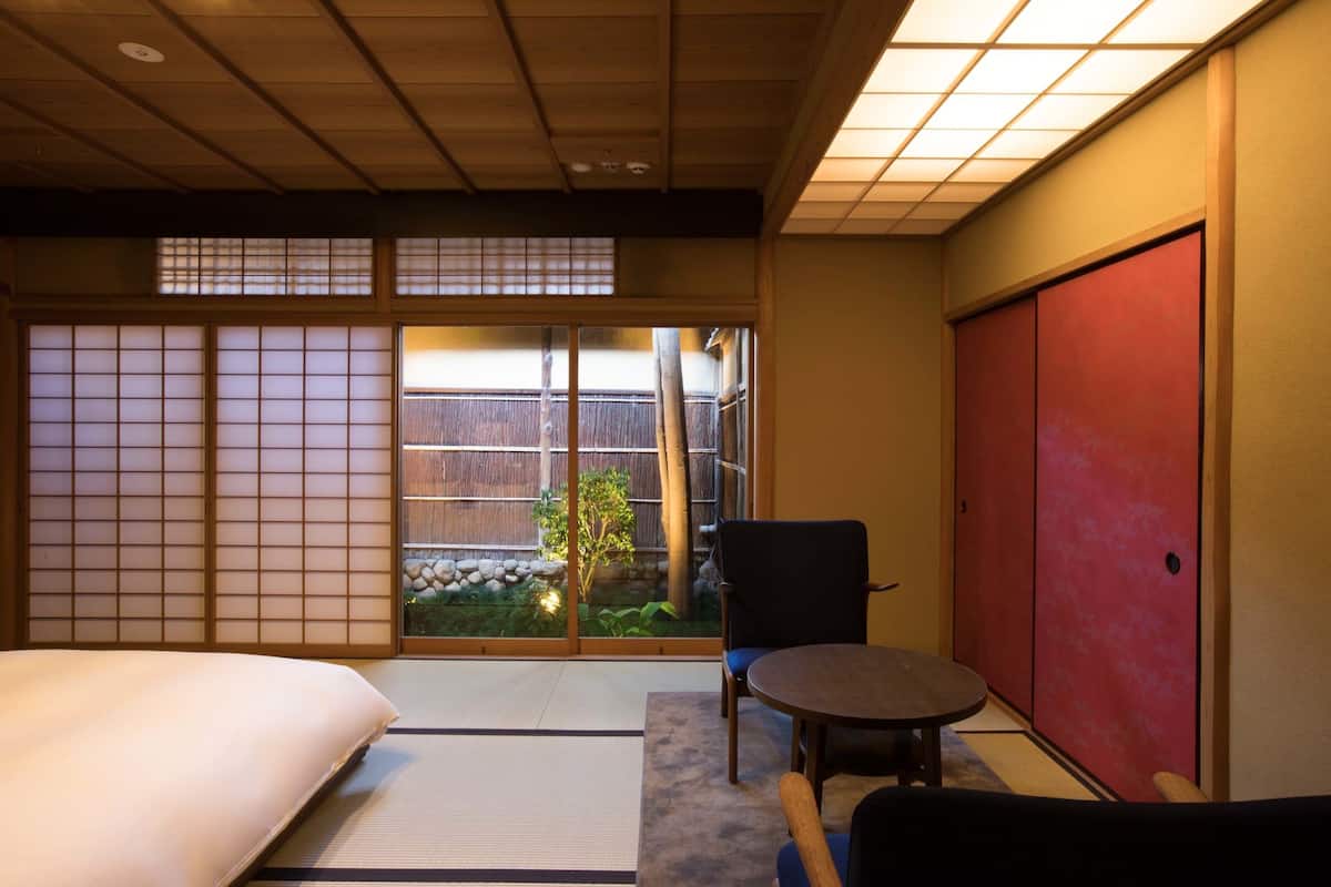 Een traditionele Japanse kamer met tatami vloerbedekking, een lage tafel, een stoel en schuifdeuren.