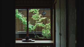 Una habitación japonesa tradicional con suelo de tatami, un shoji y vistas a un jardín por la ventana.