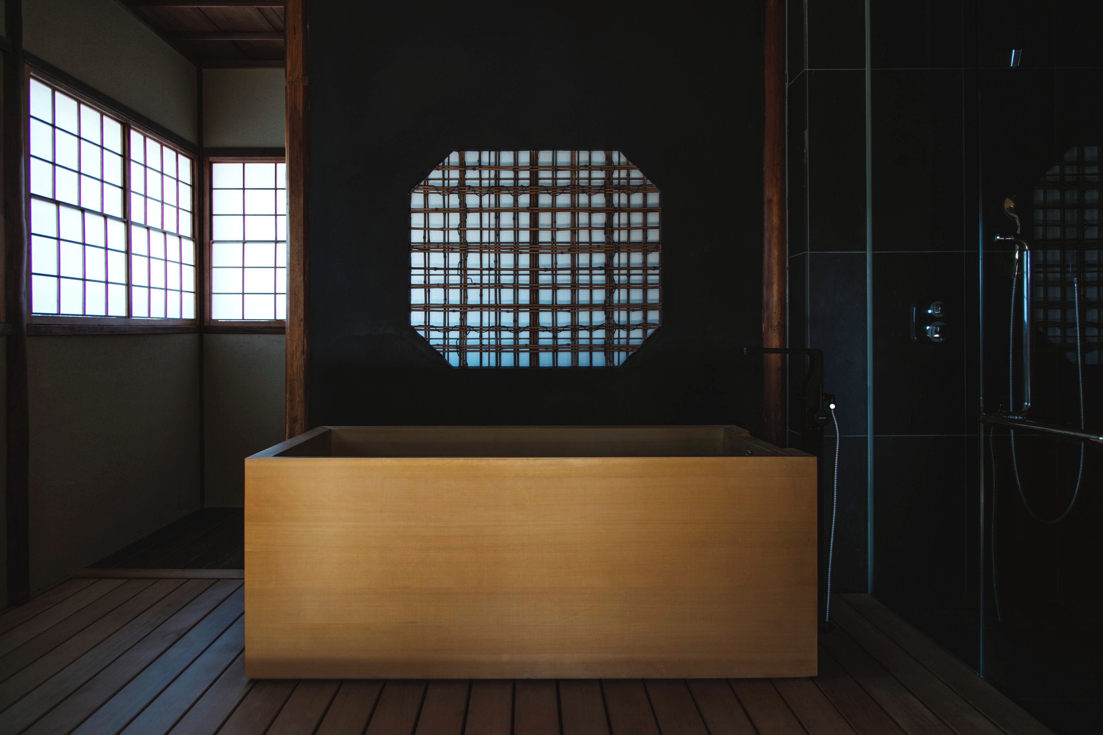 Une salle de bain moderne avec une baignoire en bois, une cabine de douche en verre et une fenêtre de style japonais traditionnel.