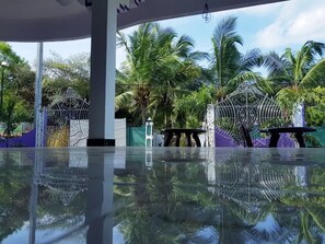 A pool area with a glass floor, surrounded by palm trees and a decorative metal fence. - SNP Star Guesthouse (Trincomalee)