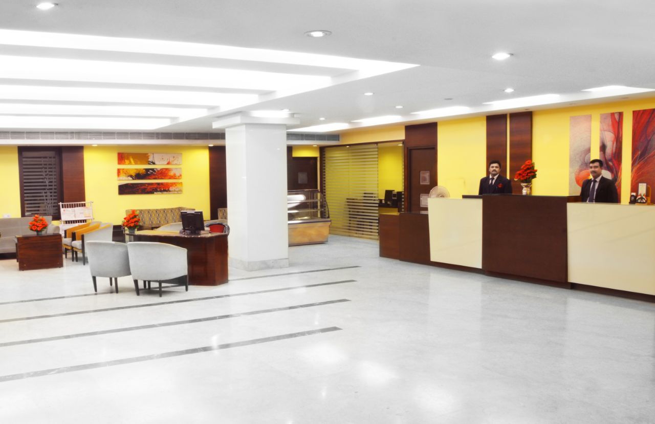 A modern hotel lobby with a reception desk, seating area, and artwork on the walls.