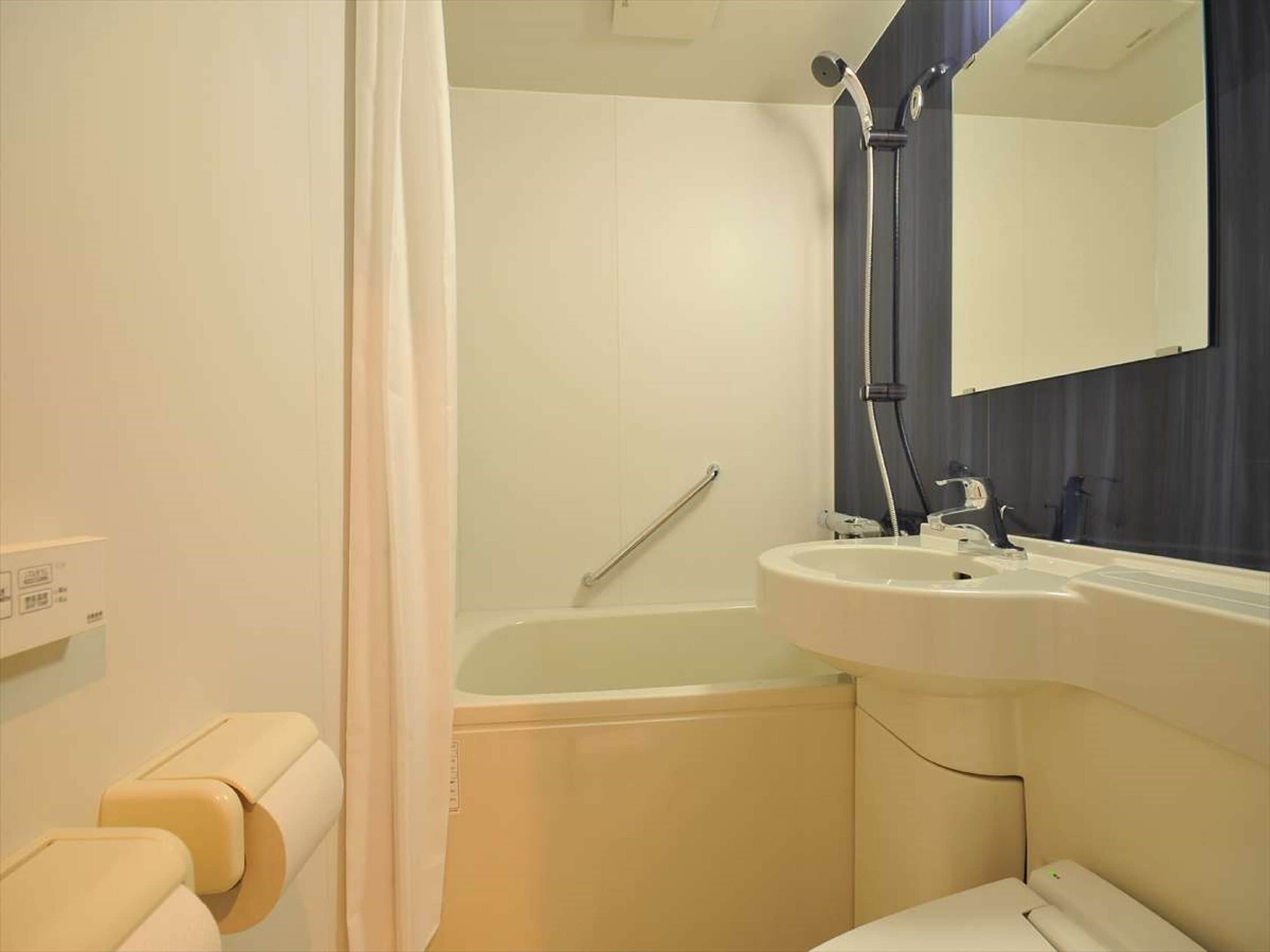 A bathroom with a bathtub, a sink, a mirror, and a toilet.