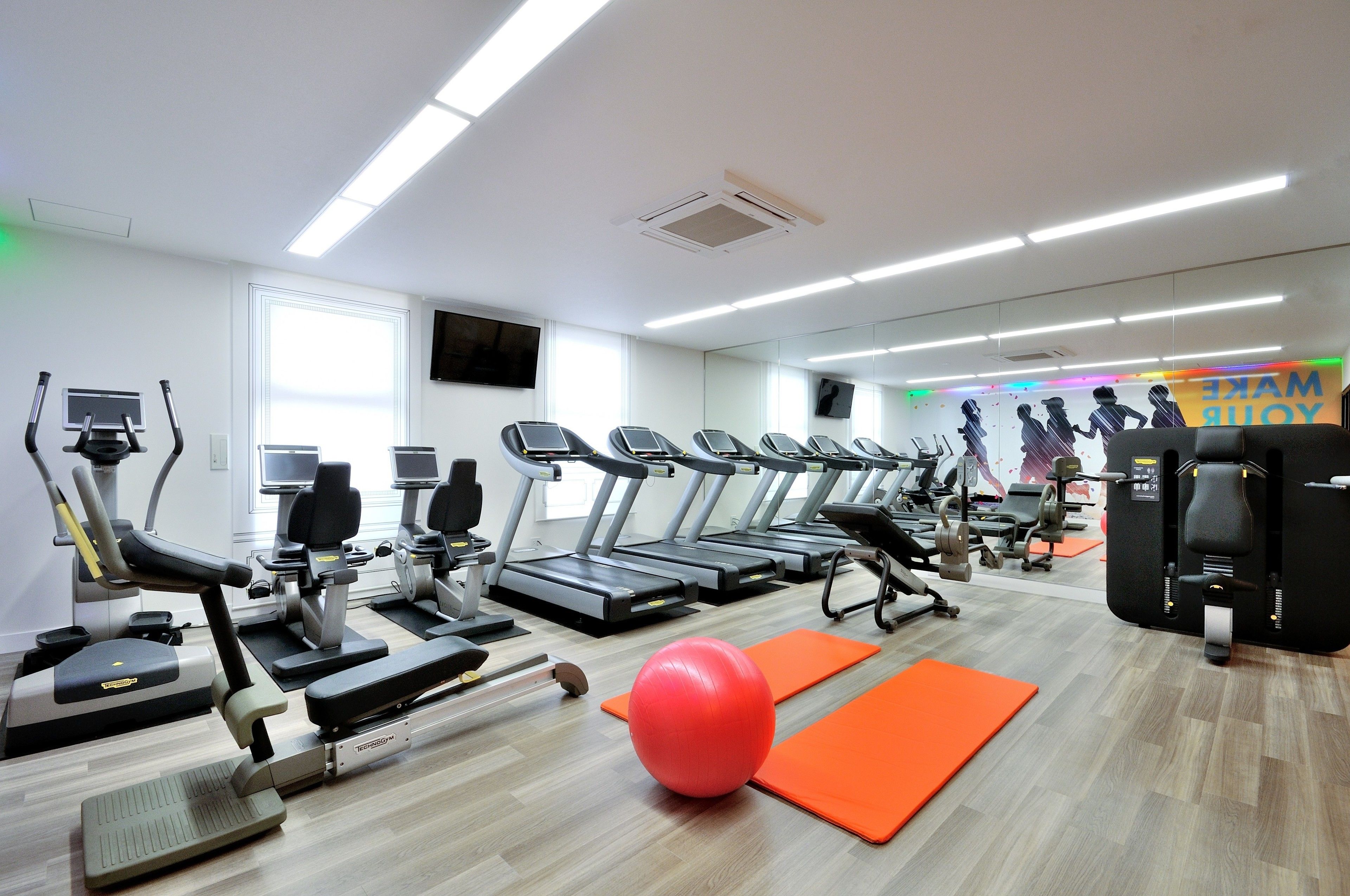Une salle de sport équipée de tapis de course, de vélos d’appartement et de ballons d’exercice.