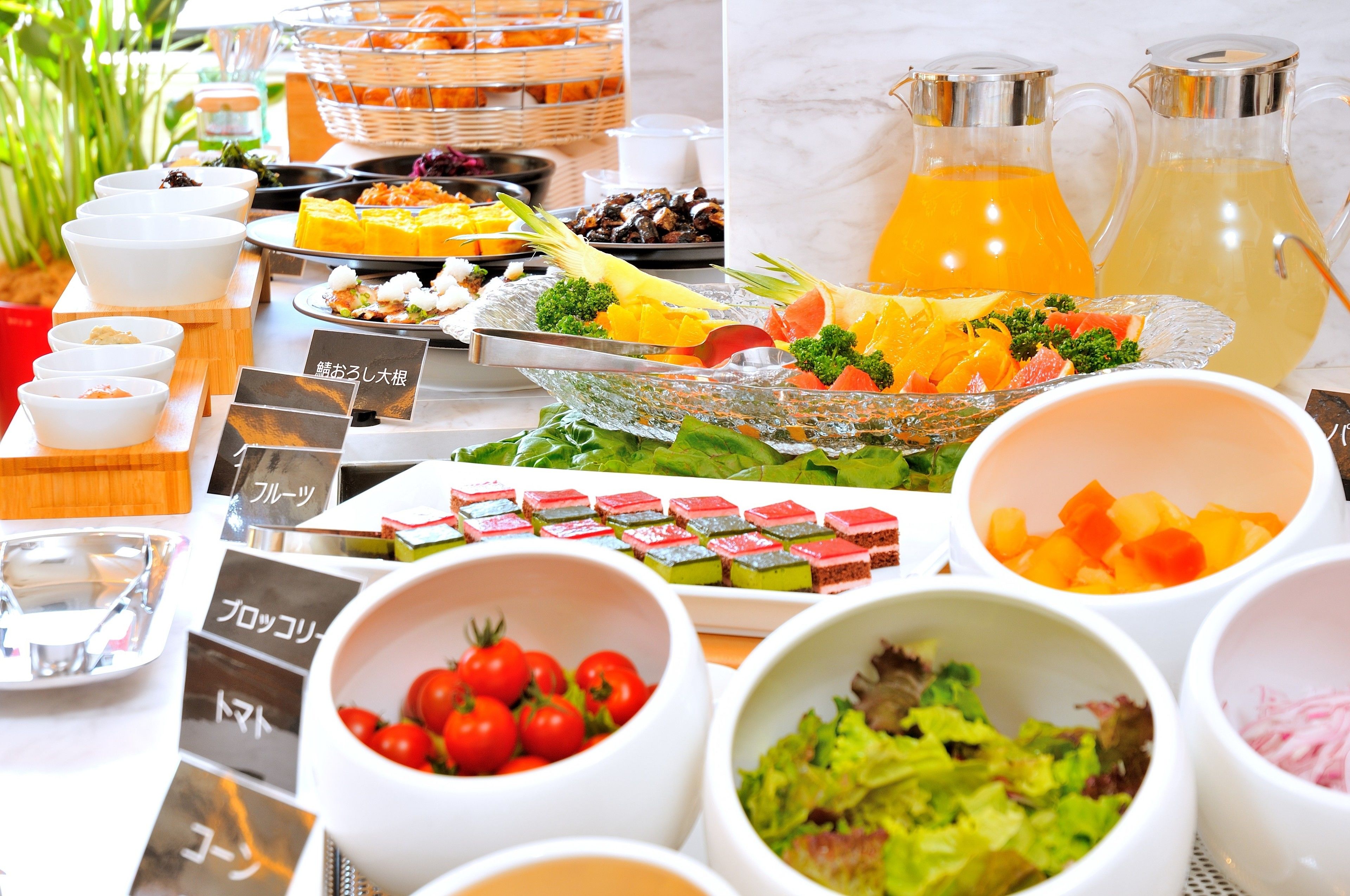 A buffet with various food items and a pitcher of orange juice.