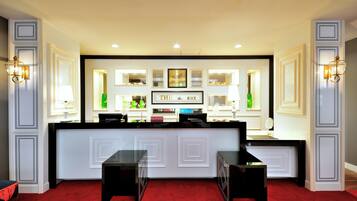 A reception area with a reception desk, two black chairs, a red carpet, and framed artwork on the wall.
