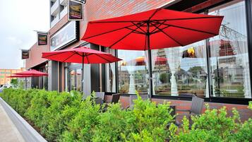 Un restaurant avec une terrasse et des parasols rouges.