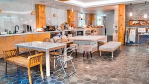 Una cocina moderna con detalles de madera, una zona de comedor con una mesa y sillas, y un perchero.