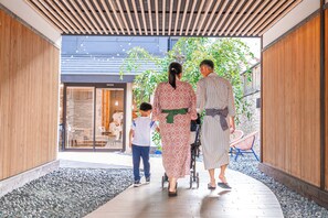 A covered walkway with wooden slats, a stone wall, and a glass door leading to a room with a stone facade. - Hotel Imagine Kyoto (Kyoto)