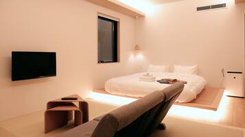 A modern hotel room with a bed, a TV, a desk, and a chair.
