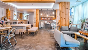 Un moderno vestíbulo de hotel con techo de madera, piso con diseño hexagonal y áreas de estar, además de una recepción visible.