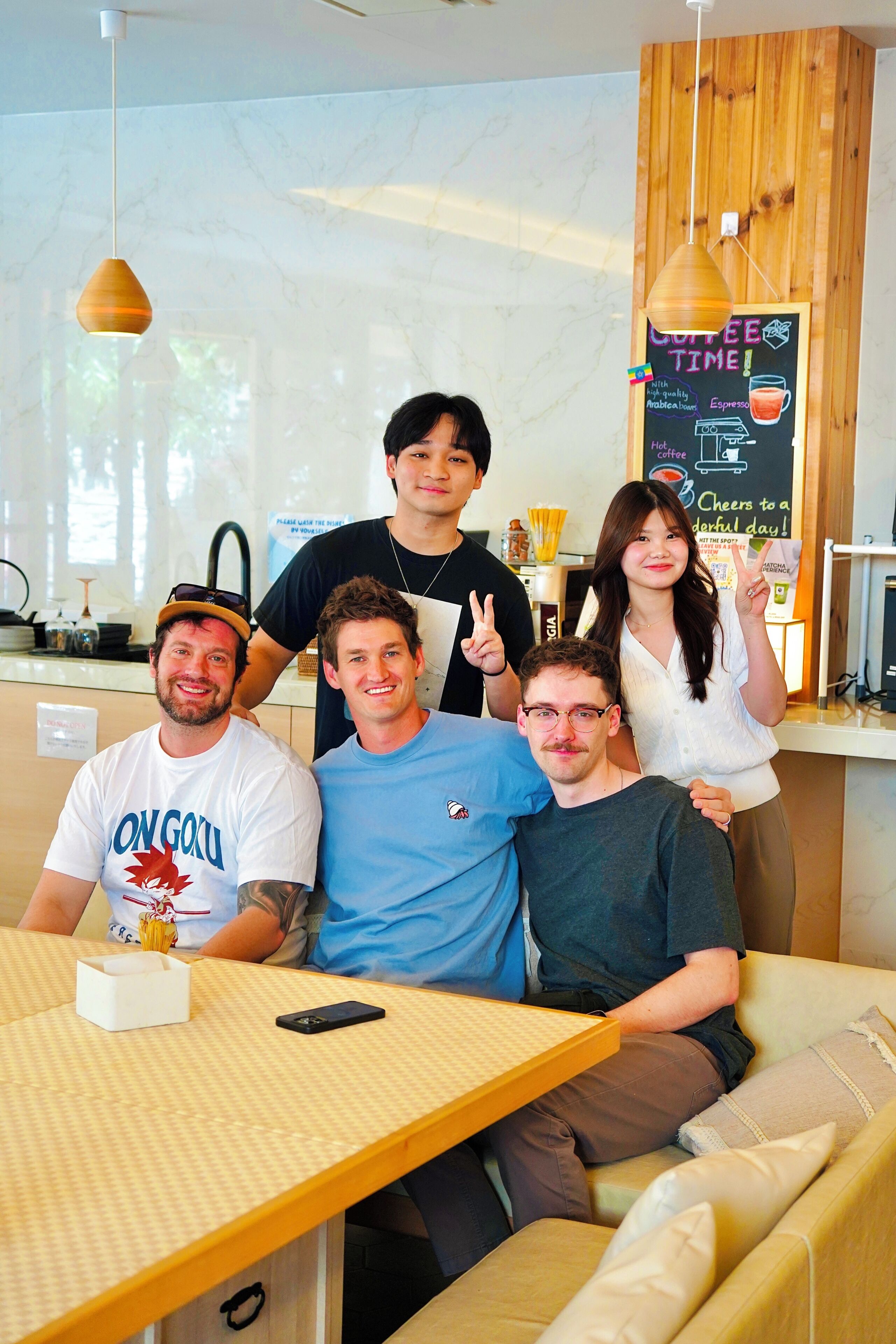 A group of people seated at a table in a cafe with a chalkboard menu and wooden accents.