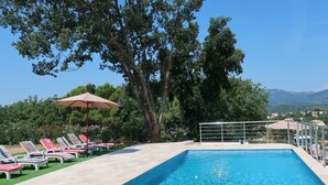 A rectangular swimming pool with a tiled edge, surrounded by a tiled deck. There are lounge chairs with red cushions and a large umbrella. - Beautiful private villa for 8 guests with A/C, WIFI, private pool, TV and terrace (Cogolin)