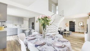 A modern kitchen with grey cabinets, a dining area with a table set for four, and a staircase leading to another level. - Beautiful private villa for 8 guests with A/C, WIFI, private pool, TV and terrace (Cogolin)
