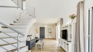 A modern living room with a staircase, a sofa, a TV, and a chandelier. - Beautiful private villa for 8 guests with A/C, WIFI, private pool, TV and terrace (Cogolin)
