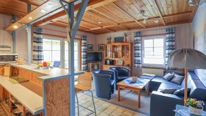 A cozy cabin interior with a dining area, seating, a television, and a bookshelf. - Stunning private villa for 5 guests with TV, patio and pets allowed (Otterndorf)