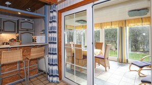A kitchen with a microwave, wicker chairs, and a sliding glass door leading to an outdoor patio with wicker furniture and a view of the garden. - Stunning private villa for 5 guests with TV, patio and pets allowed (Otterndorf)