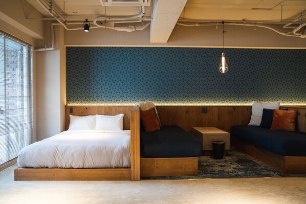 A modern bedroom with a wooden bed, a small bedside table, and a built-in bench with cushions. - SAUNALAND ASAKUSA - Hostel (Tokyo)