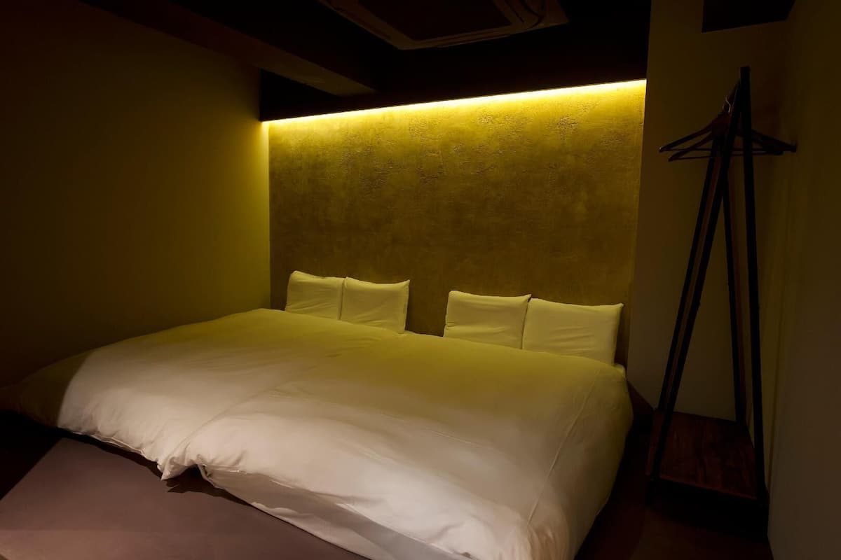 A hotel room with a bed, a headboard, and a coat rack.