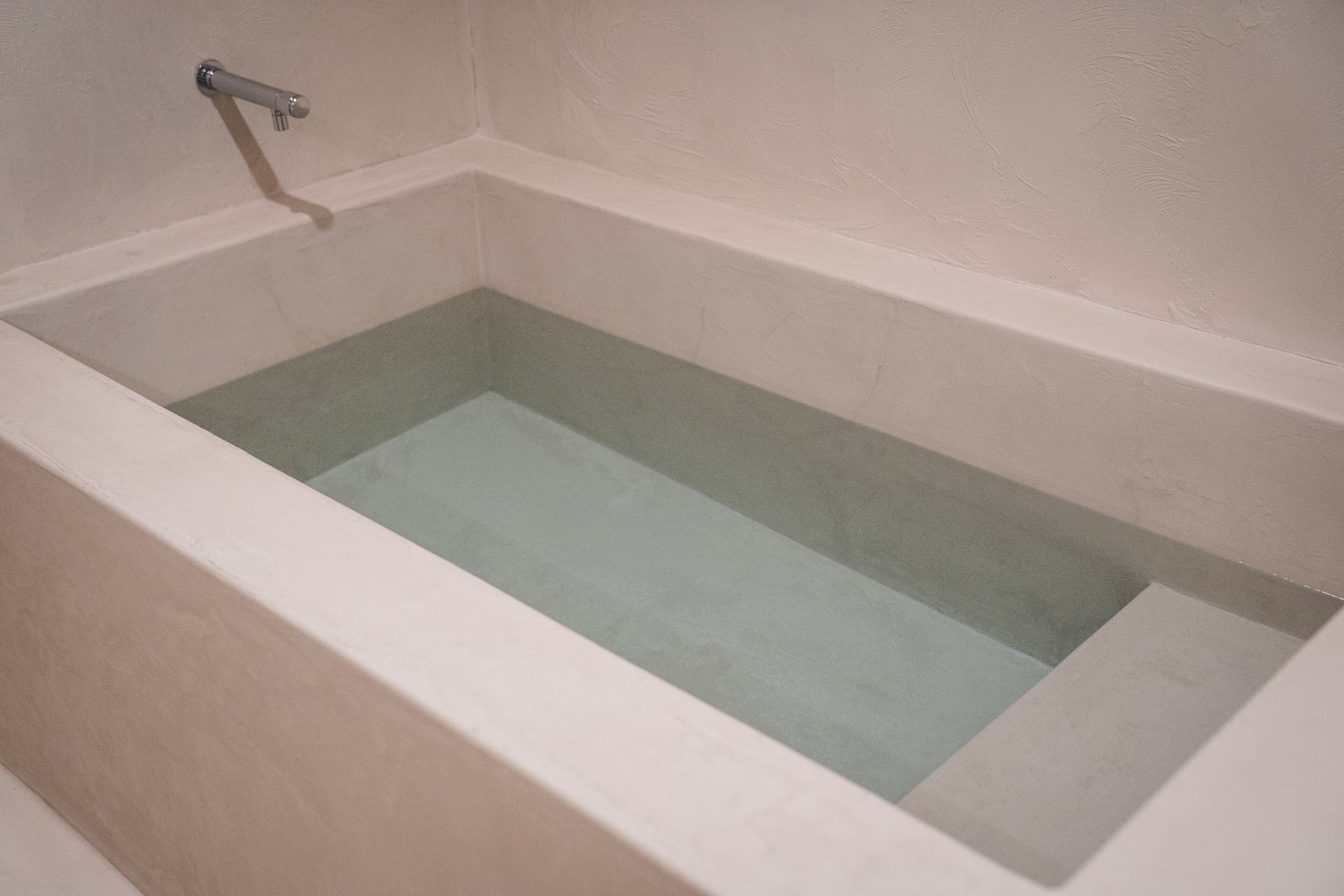 Una vasca da bagno dalla forma rettangolare e un interno liscio e di colore chiaro.