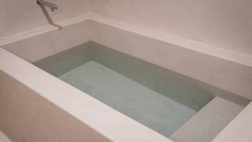 Una vasca da bagno dalla forma rettangolare e un interno liscio e di colore chiaro.