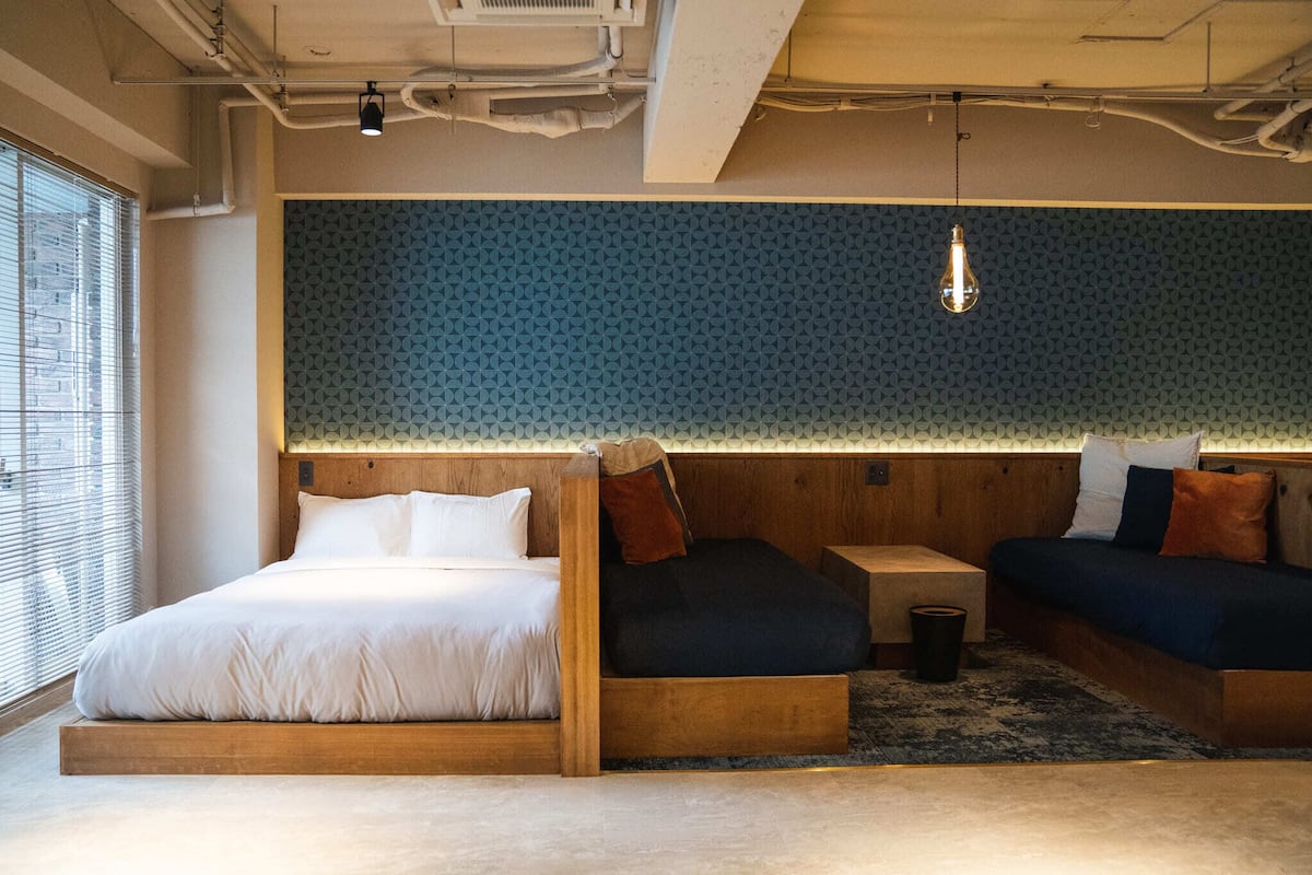A modern bedroom with a wooden bed, a sofa, and a small bedside table.