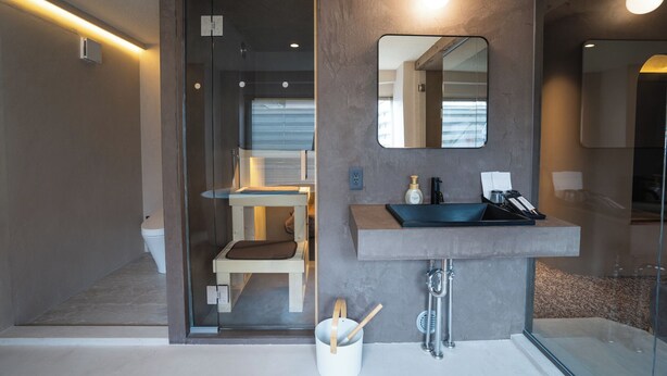 Un baño moderno con mampara de vidrio, lavamanos empotrado y espejo.
