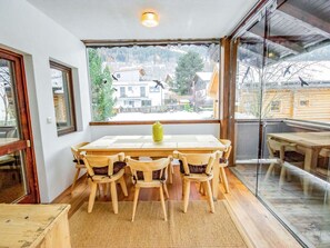 A dining area with a table and chairs, a window with a view of buildings, and a wooden floor. - Nice apartment for 7 people with WIFI, TV, balcony, pets allowed and panoramic view (Axams)