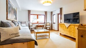 Un salon confortable avec un canapé, une table basse, un téléviseur et un tableau accroché au mur.