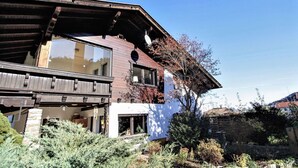A two-story house with a wooden facade, large windows, and a balcony. - Nice apartment for 7 guests with WIFI, TV, balcony, pets allowed and panoramic view (Axams)