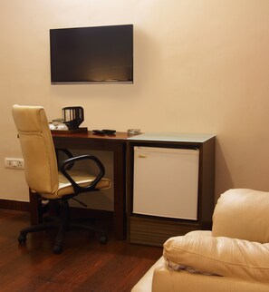 A small office space with a desk, chair, and a television mounted on the wall. - Perch Arbor Suites (Gurugram)