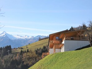 Una cabaña con balcón, con vistas a montañas nevadas y un cielo despejado.