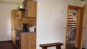 Une cuisine compacte avec des meubles de rangement en bois, un four à micro-ondes, une machine à café et un banc.
