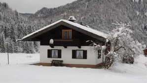Une cabane enneigée dotée d’un balcon, d’un petit porche et d’une antenne parabolique.