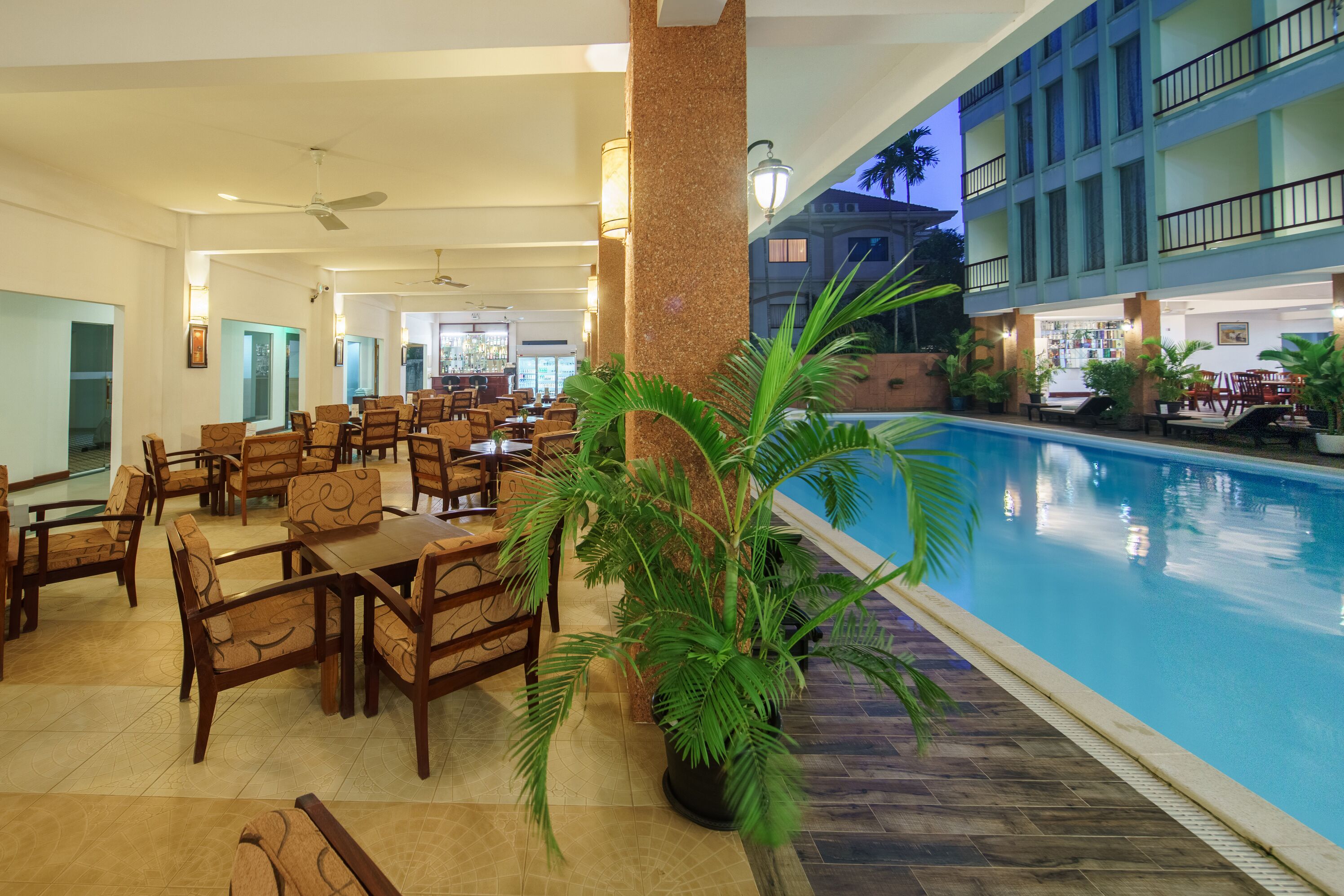 A hotel lobby with a pool, dining area, and a large pillar.