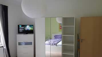 Een slaapkamer met een bed, een kledingkast, een televisie en een deur.