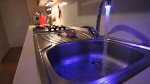 A kitchen sink with a blue underlight, a faucet, and a visible drain. - Sette sorelle b&b (Cosenza)