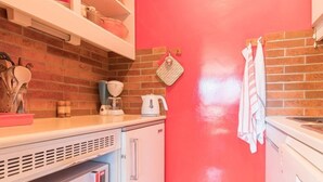 Une cuisine avec un mur rouge, des armoires blanches et un four à micro-ondes.