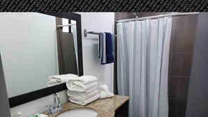 Une salle de bain moderne avec un lavabo à vasque en granit, un miroir, un porte-serviettes et un rideau de douche.