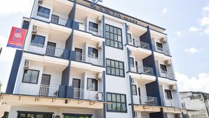 Un hotel de varios pisos con balcones, ventanas amplias y un letrero que indica servicio las 24 horas.